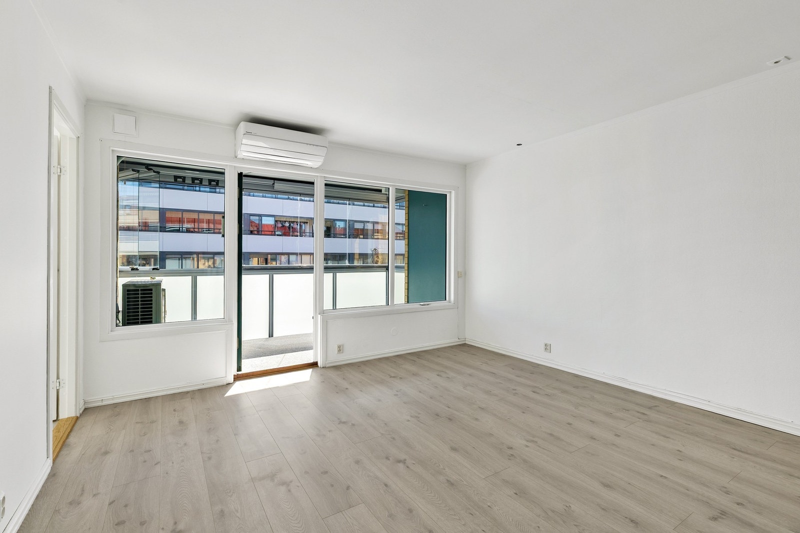 Lys stue med store vinduer som sørger for godt lysinnslipp. Det ble installert varmepumpe i stuen i 2024. Galleribilde