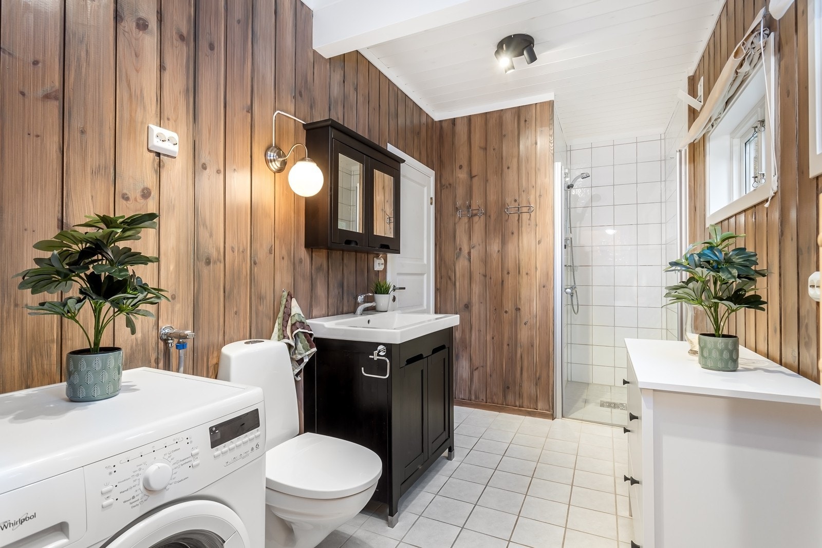 Badet er innbydende innredet med servantskap med heldekkende servant, overskap med speil, dusjnisje, toalett og opplegg for vaskemaskin. Galleribilde