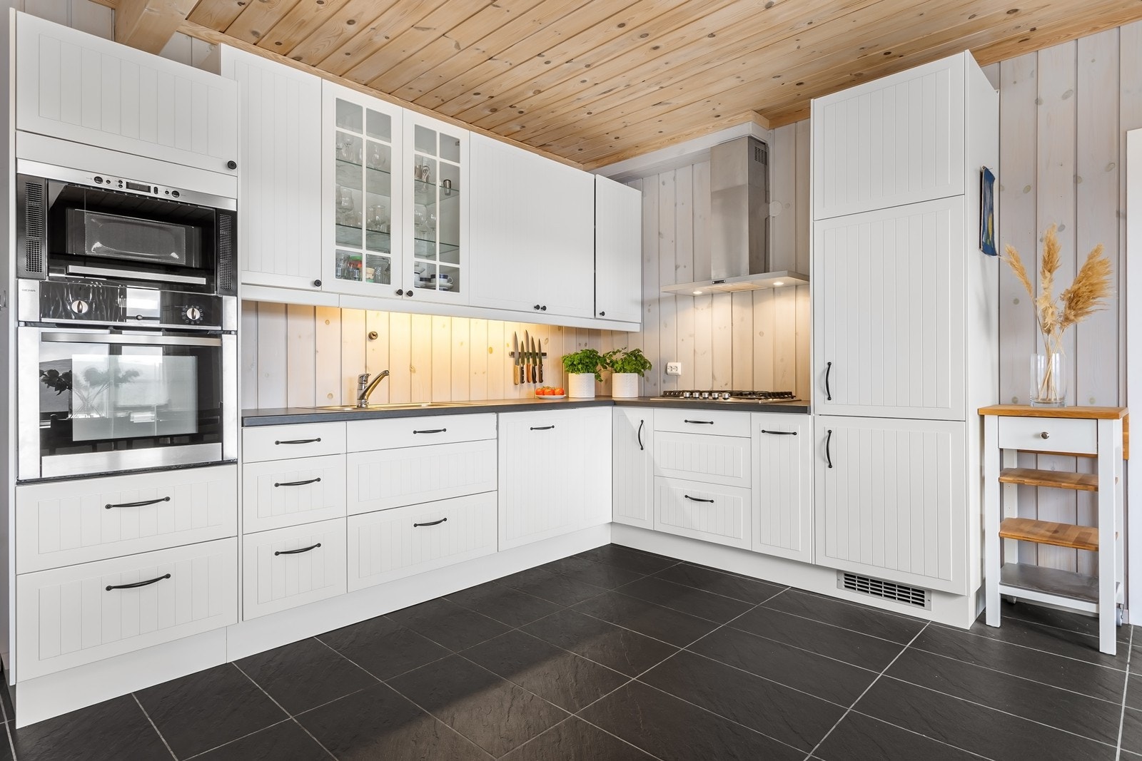 Klassisk kjøkkeninnredning med profilerte fronter og integrerte hvitevare som kjøl/fryseskap og oppvaskmaskin, stekeovn, mikro og gass koketopp. Galleribilde