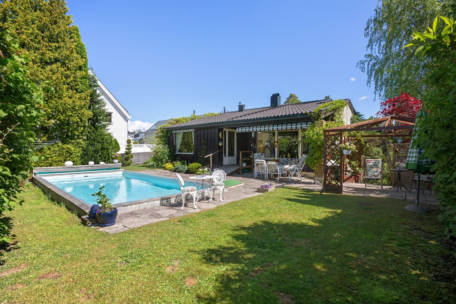 Skjermet og solrik tomt med basseng og flotte uteområder med plass til møblering i flere soner Galleribilde