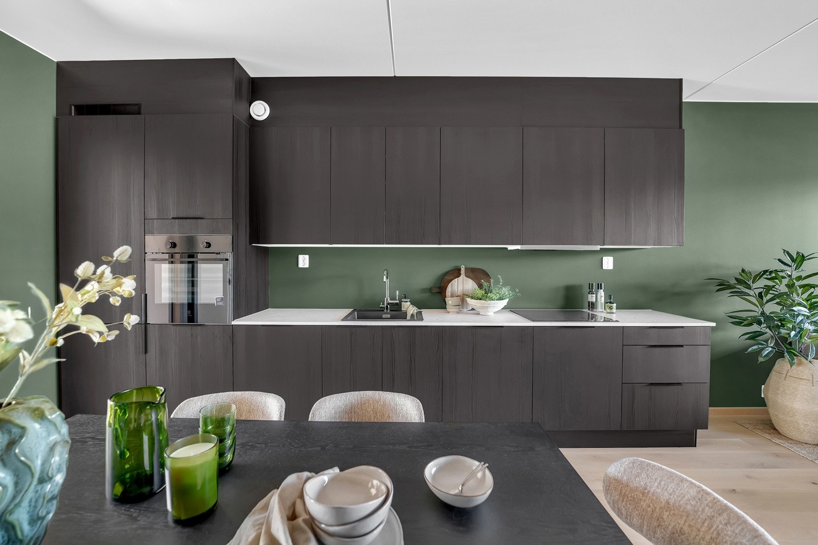 Praktisk og moderne kjøkkeninnredning fra HTH med laminat benkeplate i fargen sandsten også fra HTH. Integrerte hvitevarer som komfyr, induksjons koketopp, oppvaskmaskin og kjøl-/fryseskap Galleribilde