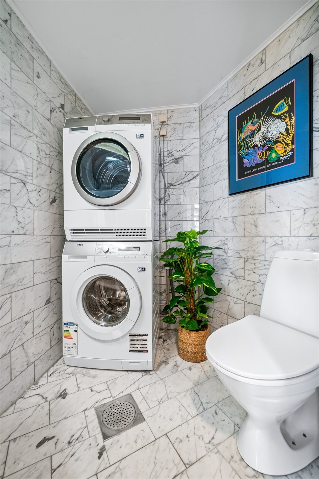 Separat vaskerom/toalettrom med fliser på gulv og vegger. Praktisk innredet med servant, gulvstående toalett og opplegg for vaskemaskin. Galleribilde