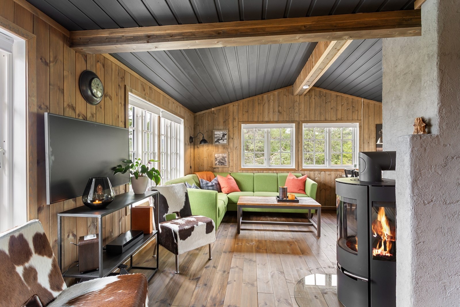 Innbydende stue med gulv av furu og trepanel på vegg. Galleribilde