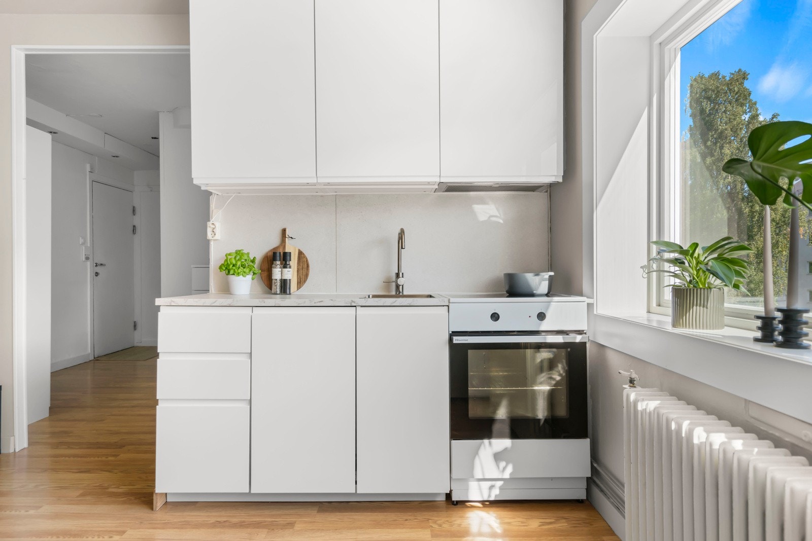 Innredningen har hvite, grepsfrie fronter, overskap med benkebelysning, oppvaskmaskin og veggplater Galleribilde