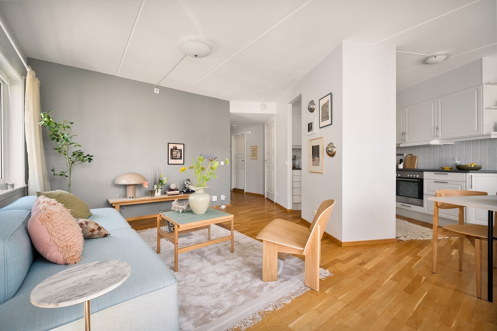 Fra denne vinkelen ser man tydelig hvordan stue og kjøkken henger naturlig sammen. Åpenheten skaper en sosial arena hvor både gjester og hverdagen får gode rammer. Galleribilde