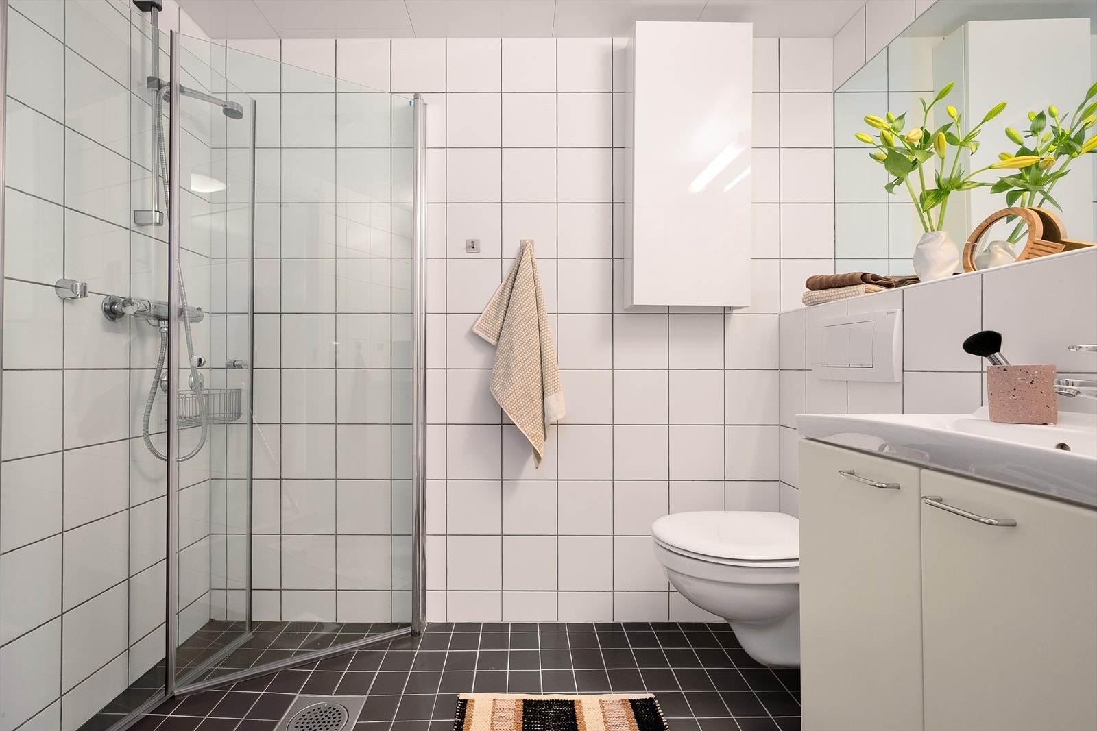 Badet fremstår delikat og moderne, med lyse fliser, vegghengt toalett og et stort speil som gir en luksuriøs følelse. Galleribilde