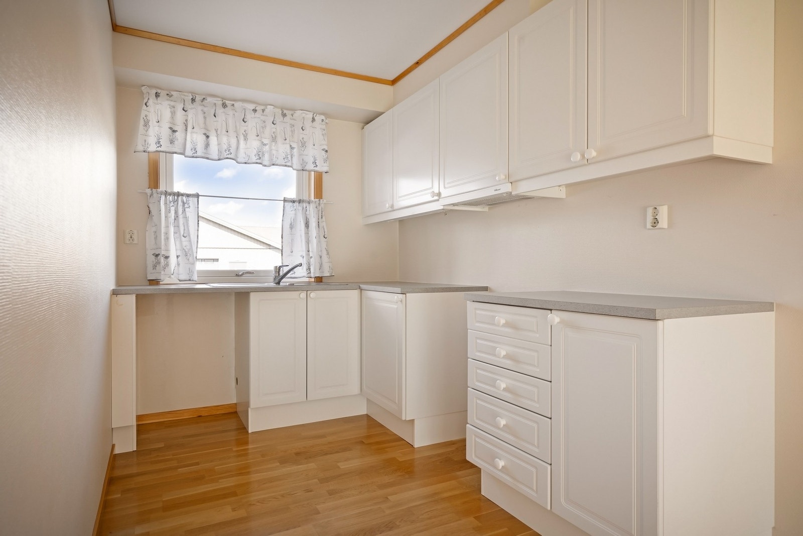 Kjøkkeninnredningen har lyse fronter med profilering. Det er plass til frittstående hvitevarer. Galleribilde