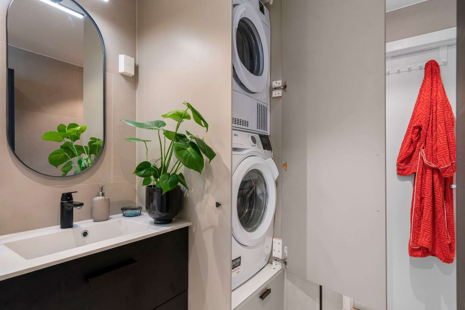 Smart løsning med plassbygd skap som både gir oppbevaring og skjuler vaskemaskin og tørketrommel. Galleribilde