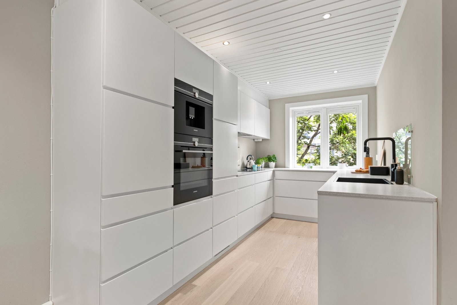 Integrerte hvitevarer som komfyr, kaffemaskin, induksjonstopp, kjøl/frys og oppvaskmaskin Galleribilde