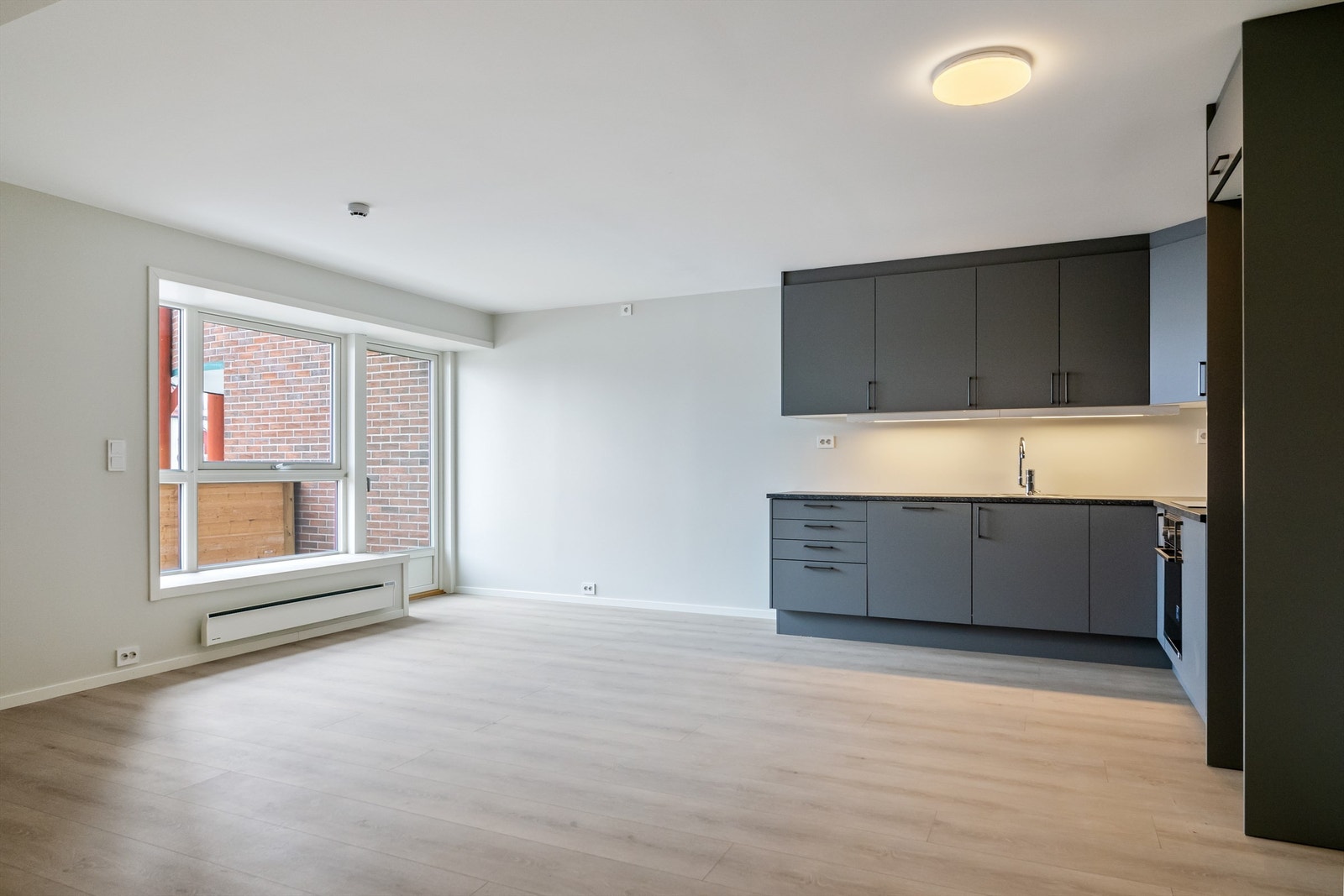 Moderne leilighet med åpen stue- og kjøkkenløsning, store vinduer og lyst laminatgulv. Galleribilde