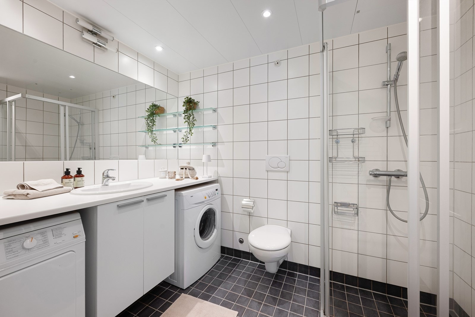 Flislagt hovedbaderom med vannbåren gulvvarme, vegghengt toalett og opplegg for vaskemaskin. Galleribilde
