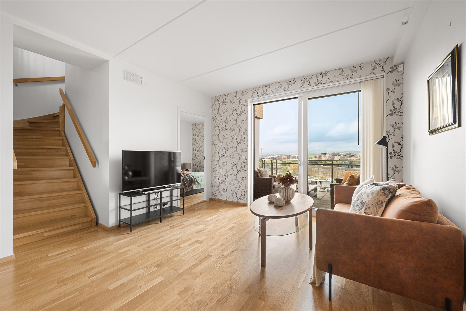 En elegant tretrapp med håndløper på begge sider leder opp til leilighetens andre plan. Galleribilde