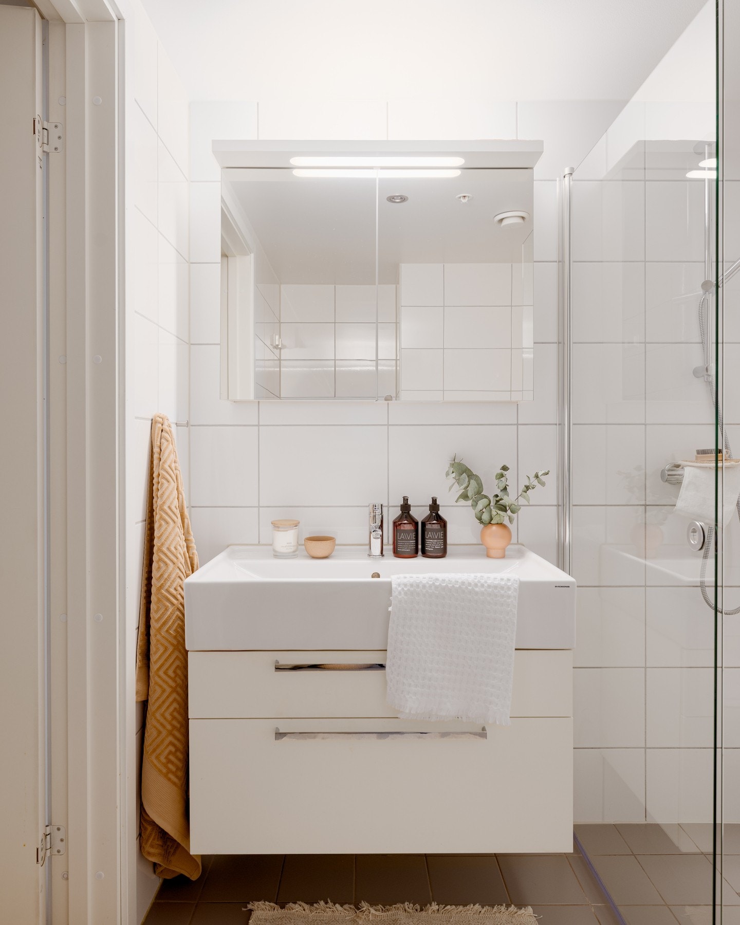 Moderne servantinnredning med glatte fronter, speilskap med belysning og praktiske oppbevaringsløsninger. Galleribilde