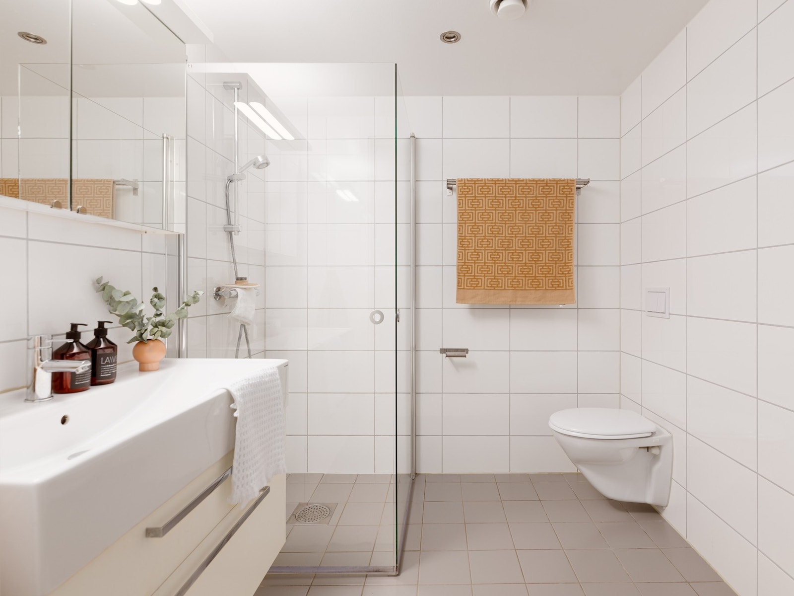 Delikat flislagt bad med varmekabler, innfellbart dusjhjørne, vegghengt toalett og servantinnredning med speilskap. Opplegg for vaskemaskin Galleribilde