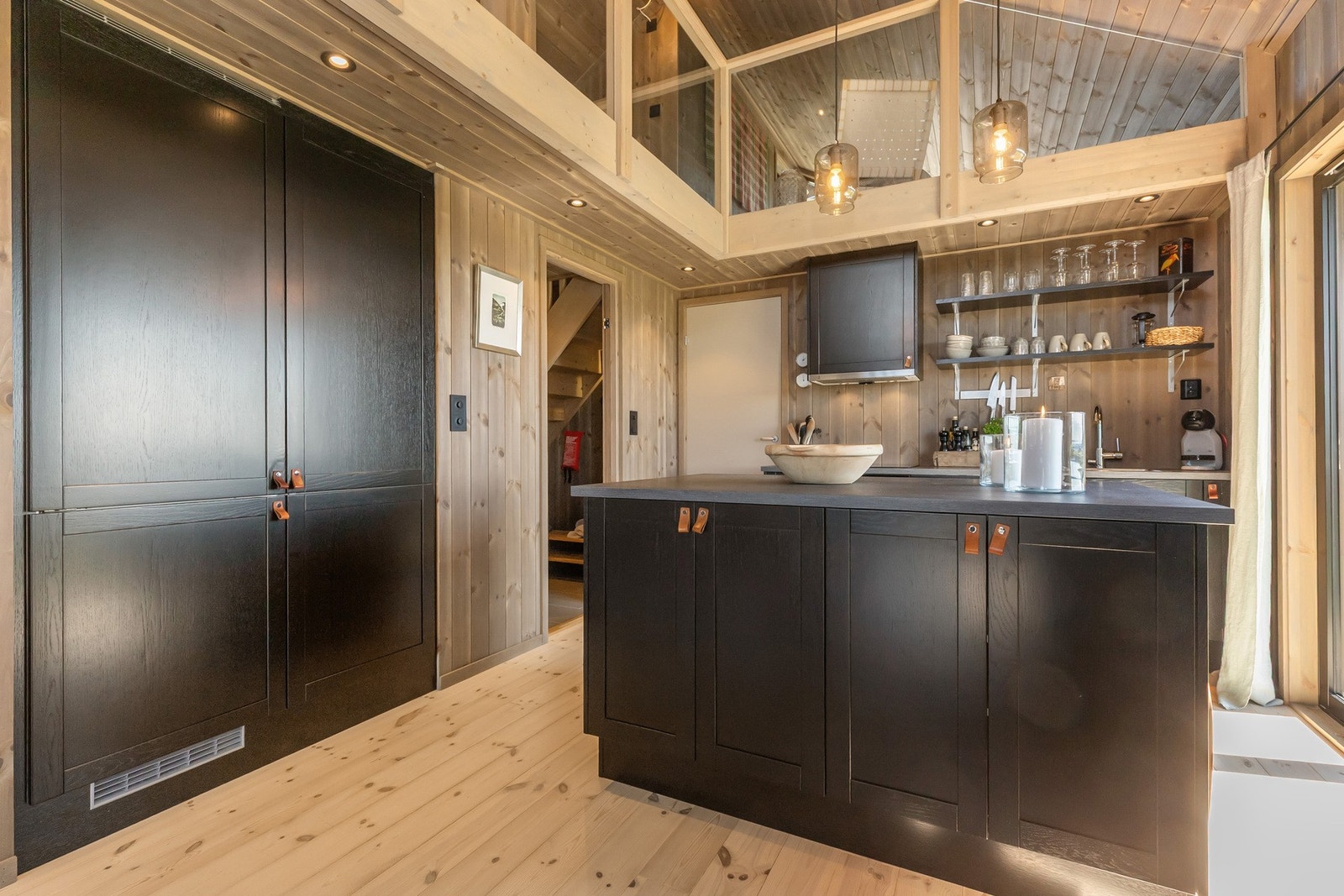 Langs den ene veggen er det plassbygd høyskap og intergrert kjøleskap som utnytter arealet effektivt Galleribilde