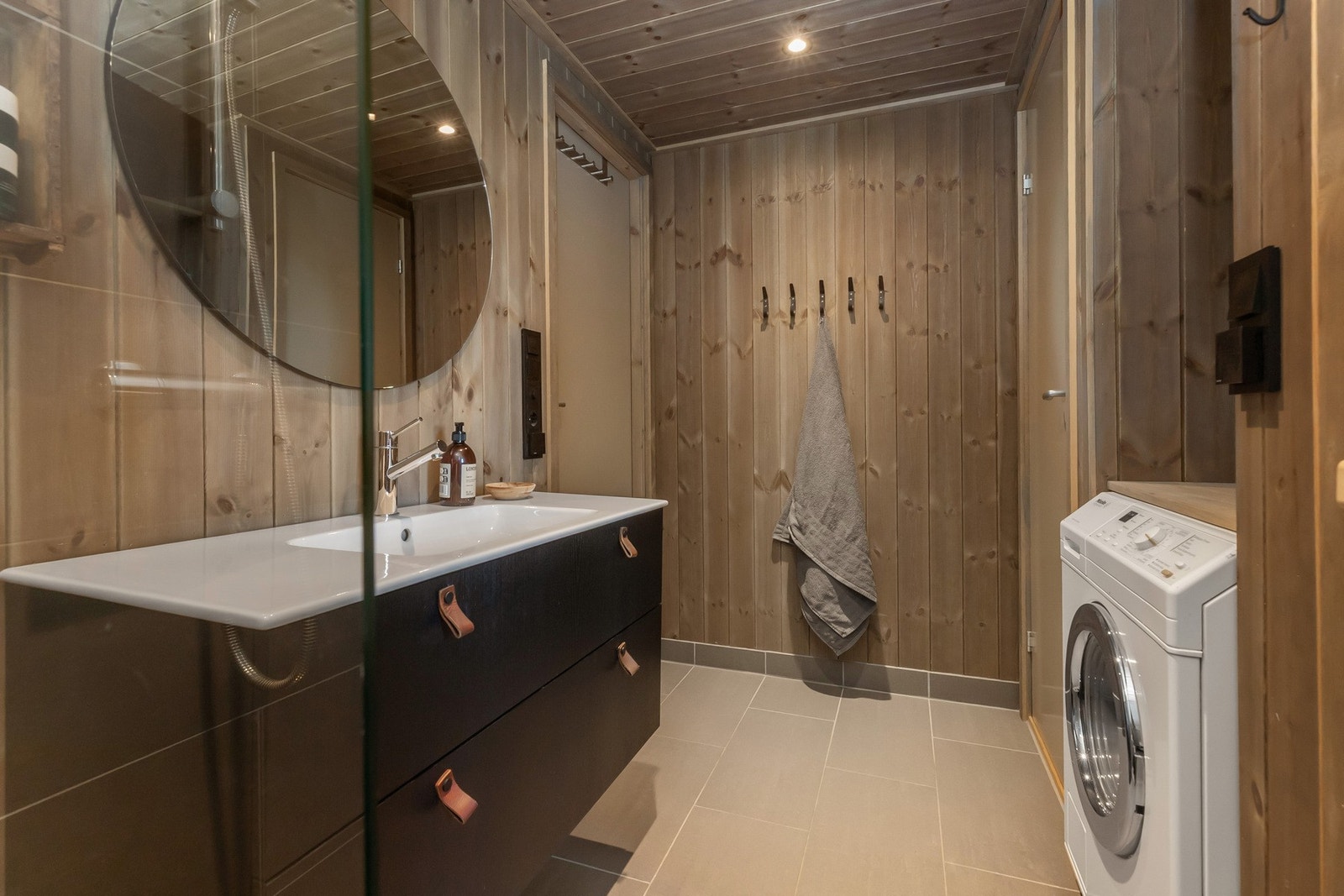 Badet har flott innredning i sort med underskuffer og nedfelt servant i benk Galleribilde