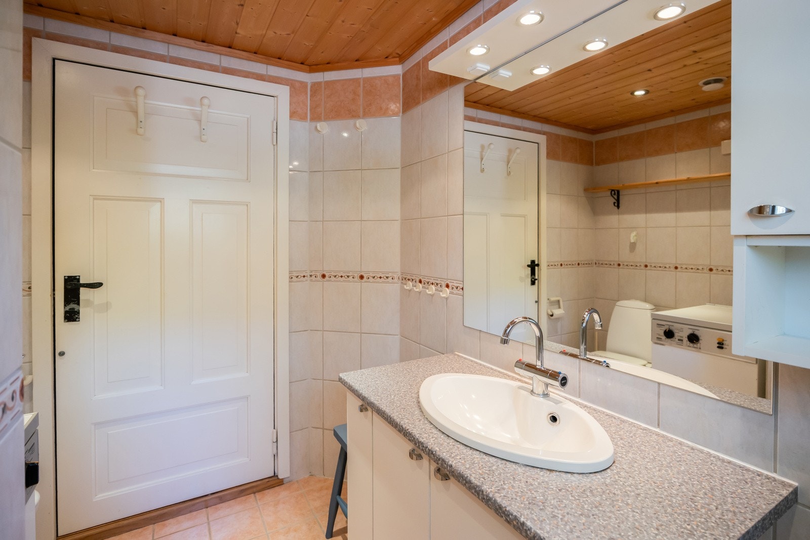 Flislagt bad som er utstyrt med gulvvarme, toalett, dusjnisje, servant og opplegg for vaskemaskin. Galleribilde