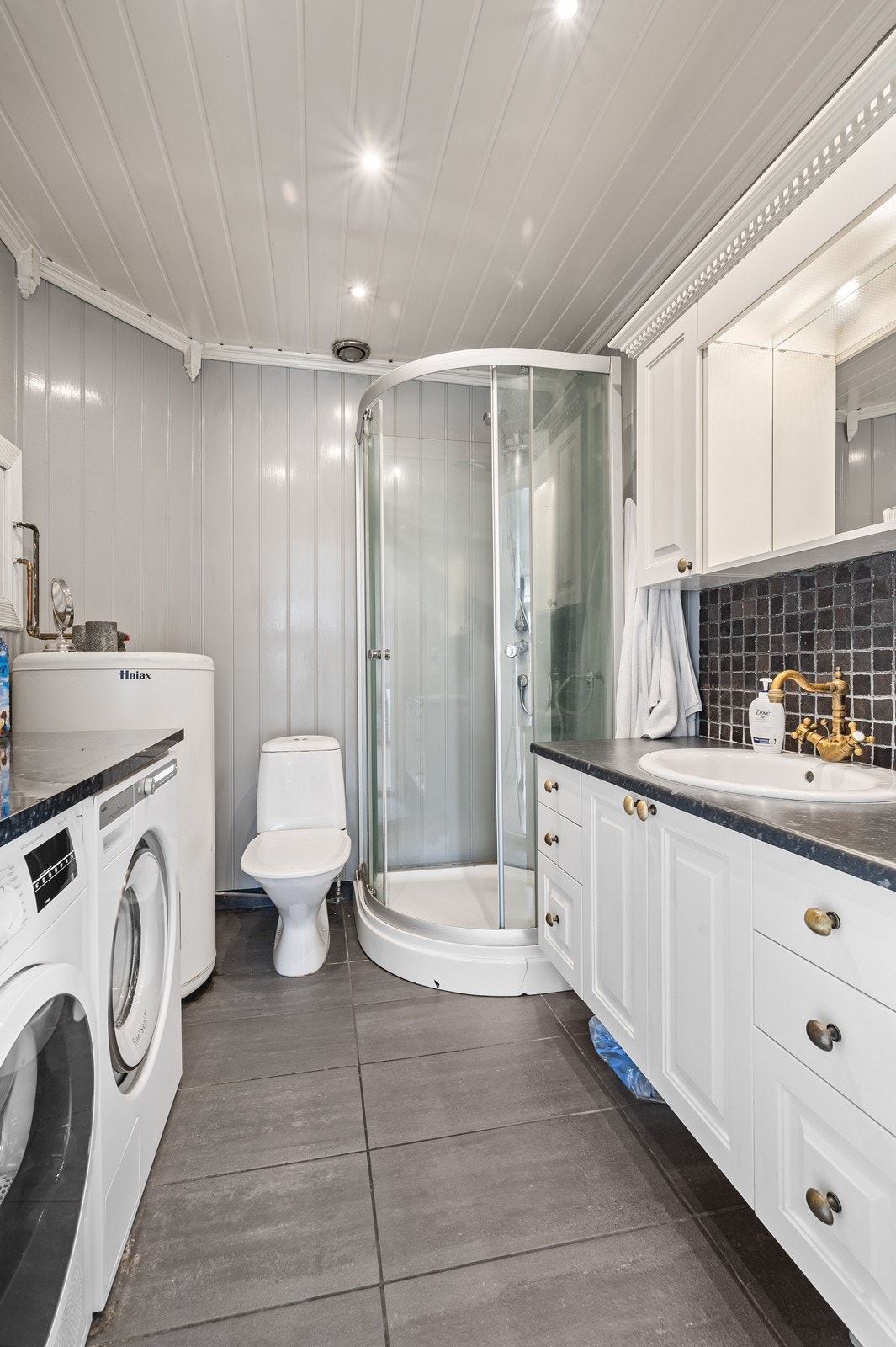 Badet inneholder wc, dusjkabinett og håndvask med skap. Opplegg for vaskemaskin og tørketrommel. (Vaskemaskin/ tørketrommel medfølger ikke). Galleribilde