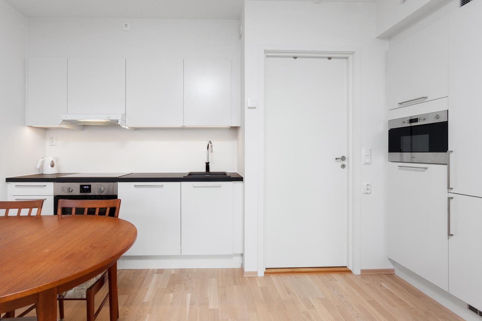 Stue mot kjøkken med integrerte hvitevarer Galleribilde