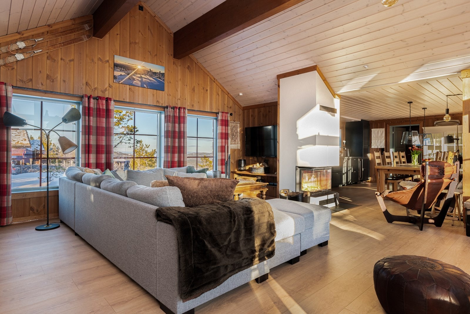 Store vinduer gir godt med lys og trekker naturen inn i stua. Det er en flott peis mellom stue og kjøkken som ses fra begge sider. Galleribilde