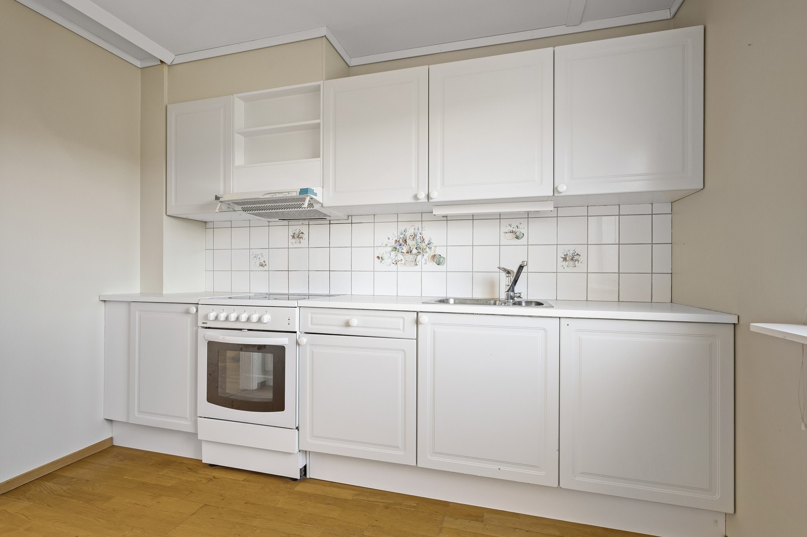 Kjøkkeninnredning med hvite, profilerte fronter og laminert benkeplate. Galleribilde