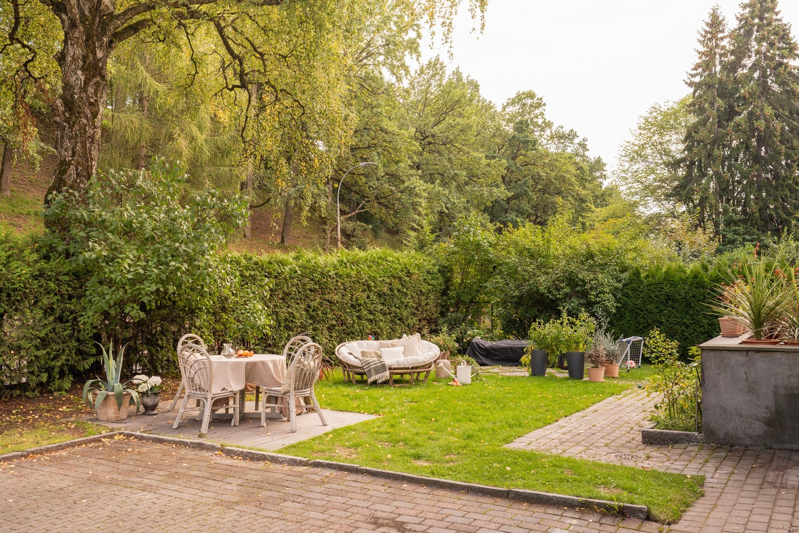 Villaen er omkranset av en idyllisk hage med plen, hekker, trær og gjerde. Galleribilde