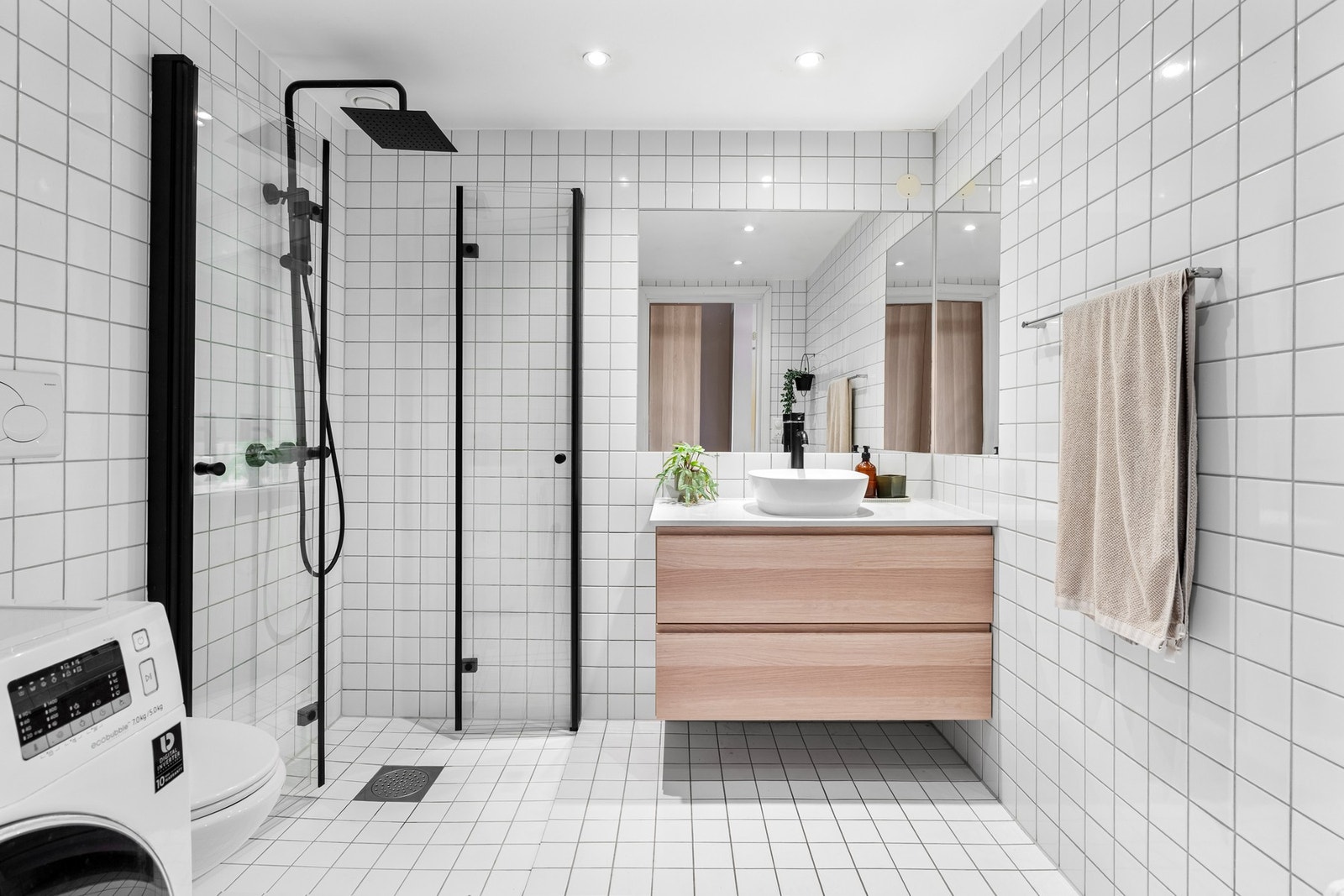 Romslig helfliset bad med elektriske varmekabler på gulv, downlights og opplegg for vaskemaskin. Galleribilde