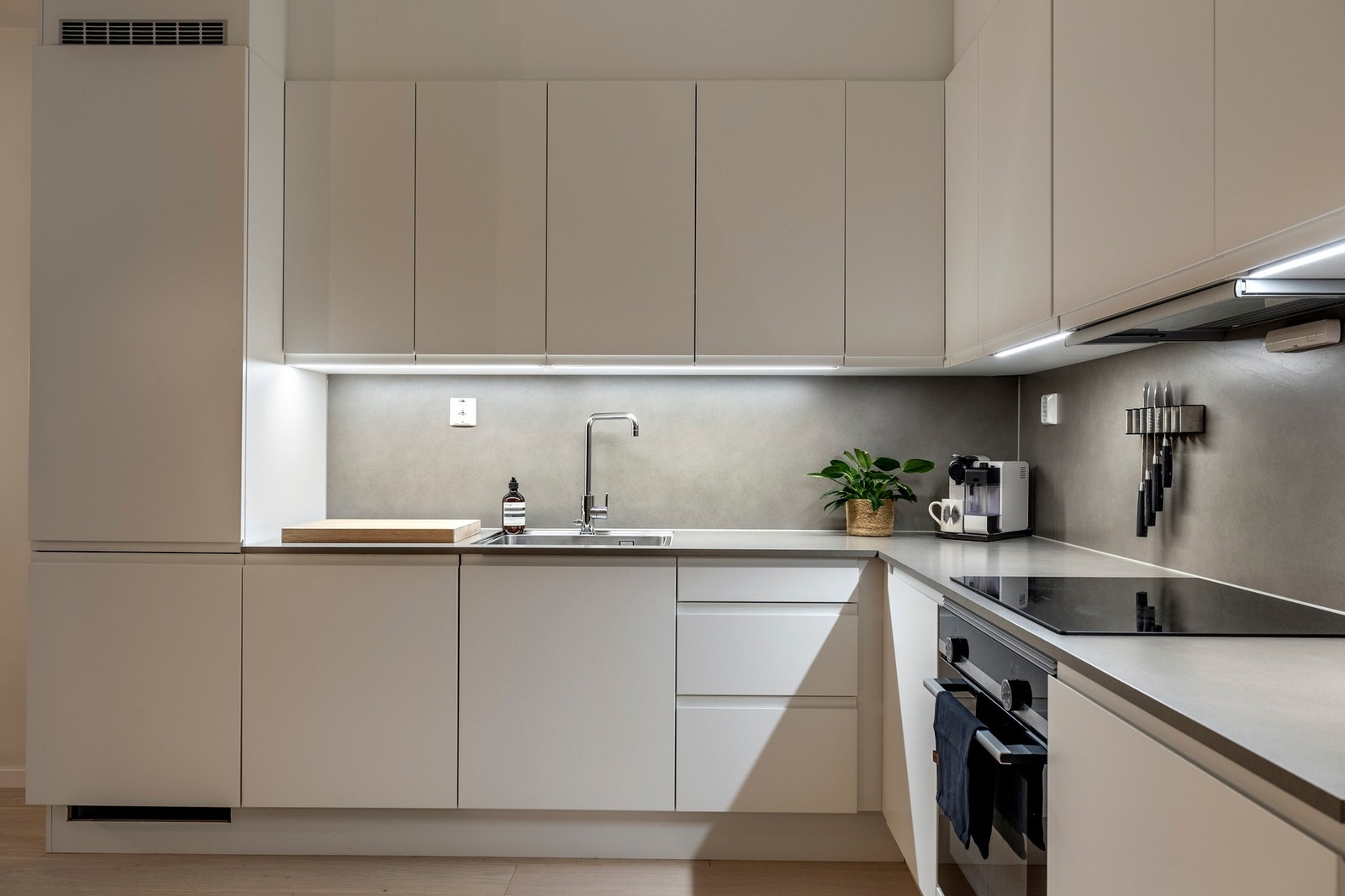 Innredningen består av glatte, hvite fronter, takoppforede skap og benkeplate i slitesterk laminat med integrert stålvask Galleribilde