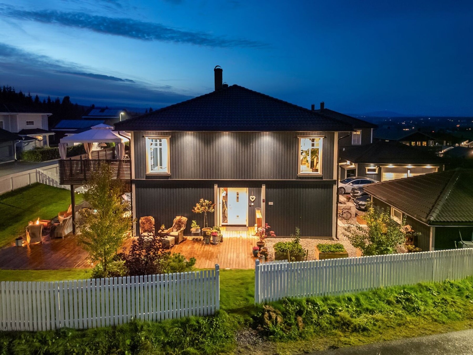 Boligen tar seg flott ut også på kveldstid, med opplyste uteområder, terrasse og veranda som skaper en helhetlig og innbydende atmosfære. Galleribilde