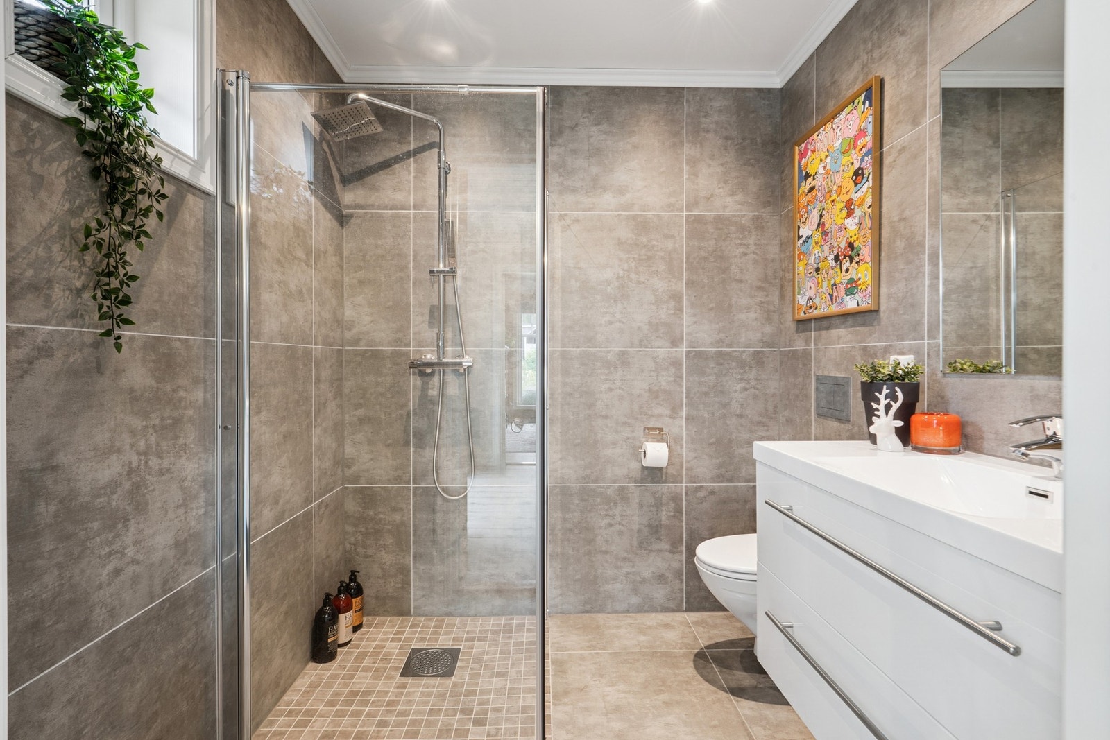 Baderommet i 2. etasje er innredet med dusjhjørne, vegghengt toalett og servant med oppbevaringsplass. Flislagte overflater gir et helhetlig uttrykk. Galleribilde