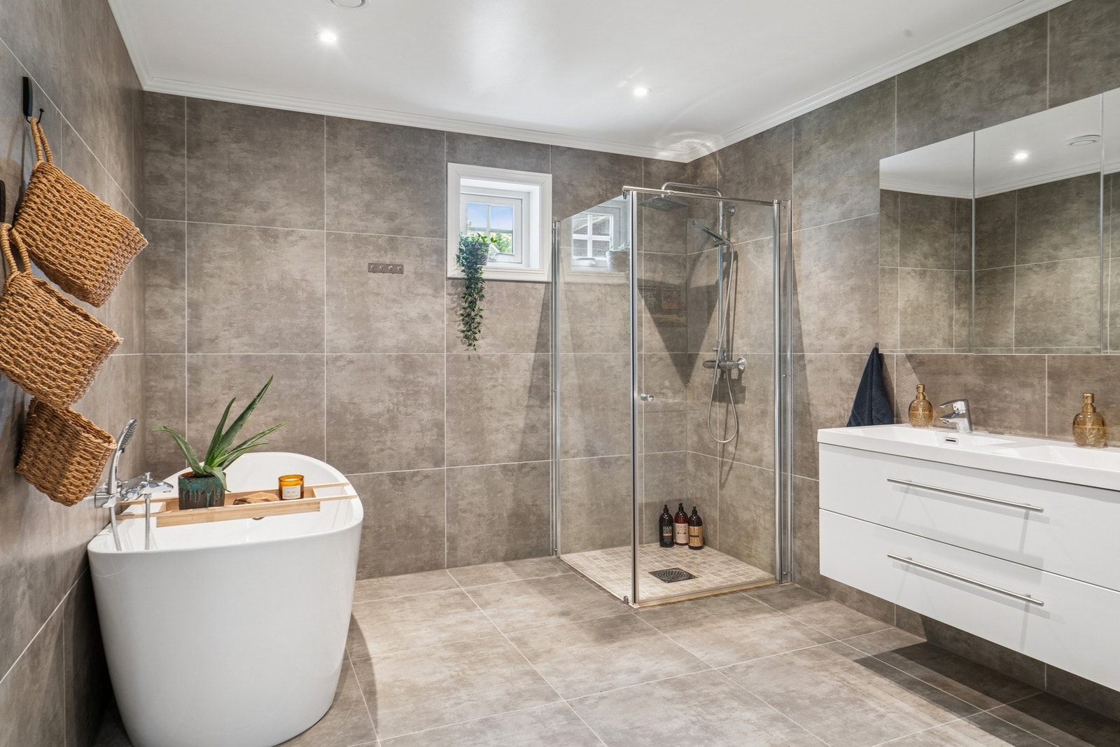 Hovedbadet i 1. etasje er romslig og innredet med dusjhjørne, frittstående badekar, vegghengt toalett og dobbel servant med skuffer. Galleribilde