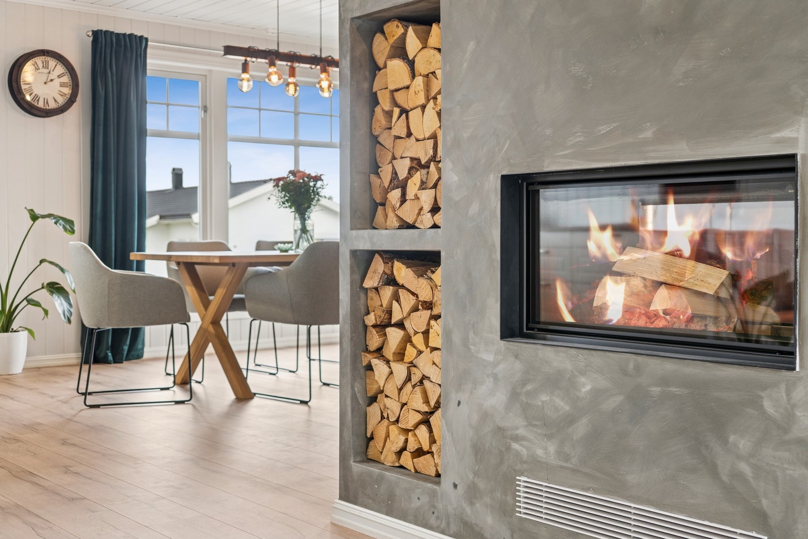 Den innebygde peisen skaper en lun atmosfære i oppholdsrommet, samtidig som den naturlig deler sonene mellom spiseplassen og stuen. Galleribilde