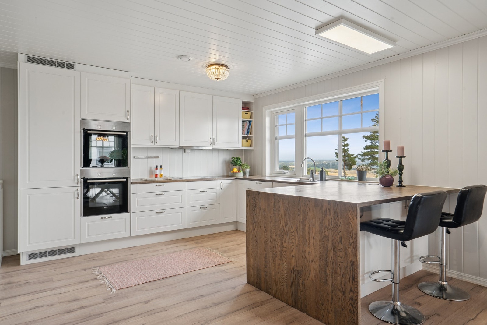 Kjøkkenet har profilerte fronter, heltre benkeplate, kjøkkenøy og integrerte hvitevarer. Galleribilde