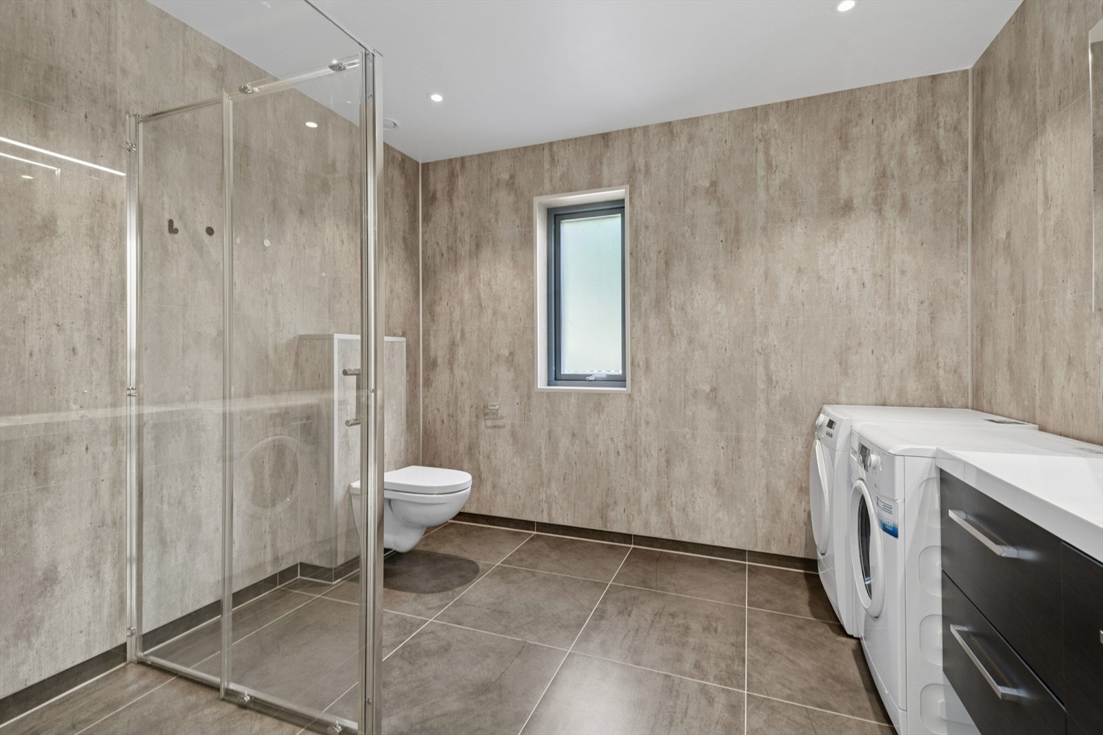 Baderommet er innredet med meget stor dusjsone med glass/skyvedør, det er satt opp dusjarmatur med regnfalldusj Galleribilde