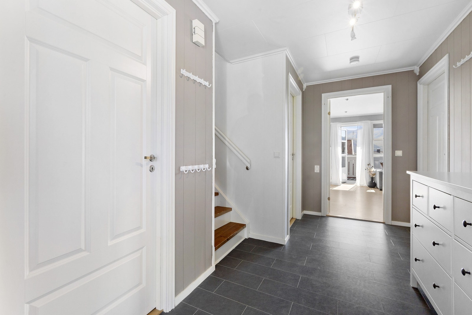 Lys og romslig hall med flislagt gulv, trappeadkomst til loftetasjen og god plass til oppbevaring Galleribilde