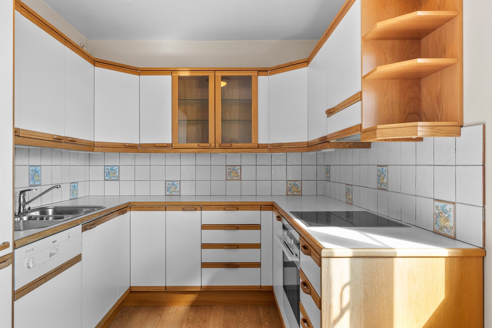 Kjøkkeninnredning med finerte fronter, laminat benkeplater, oppvaskkum, ventilator, fliser over
benk, belysning under overskap, integrert oppvaskmaskin, kjøl/fryseskap, stekeovn og keramisk platetopp. 2 fronter med glass. Galleribilde