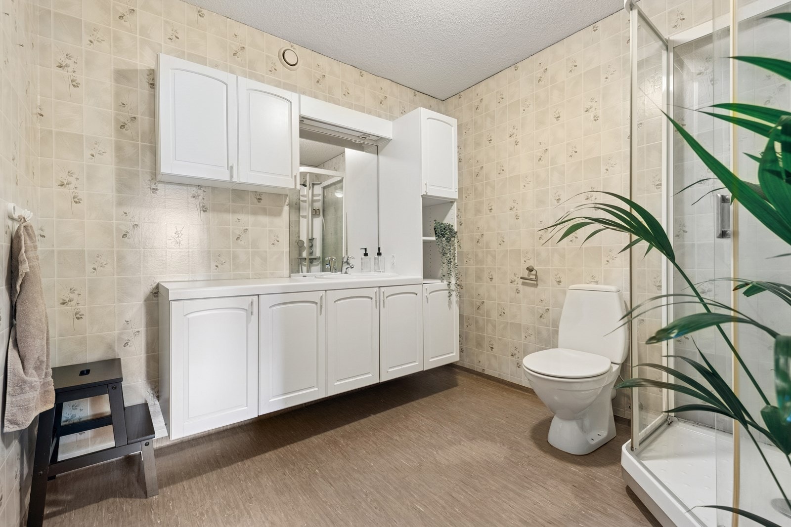 Baderommet er trolig fra byggeår og er innredet med vinylbelegg på gulv og tapet på vegg. Badet er ellers utstyrt med dusjkabinett, toalett og veggseksjon med servant. Galleribilde