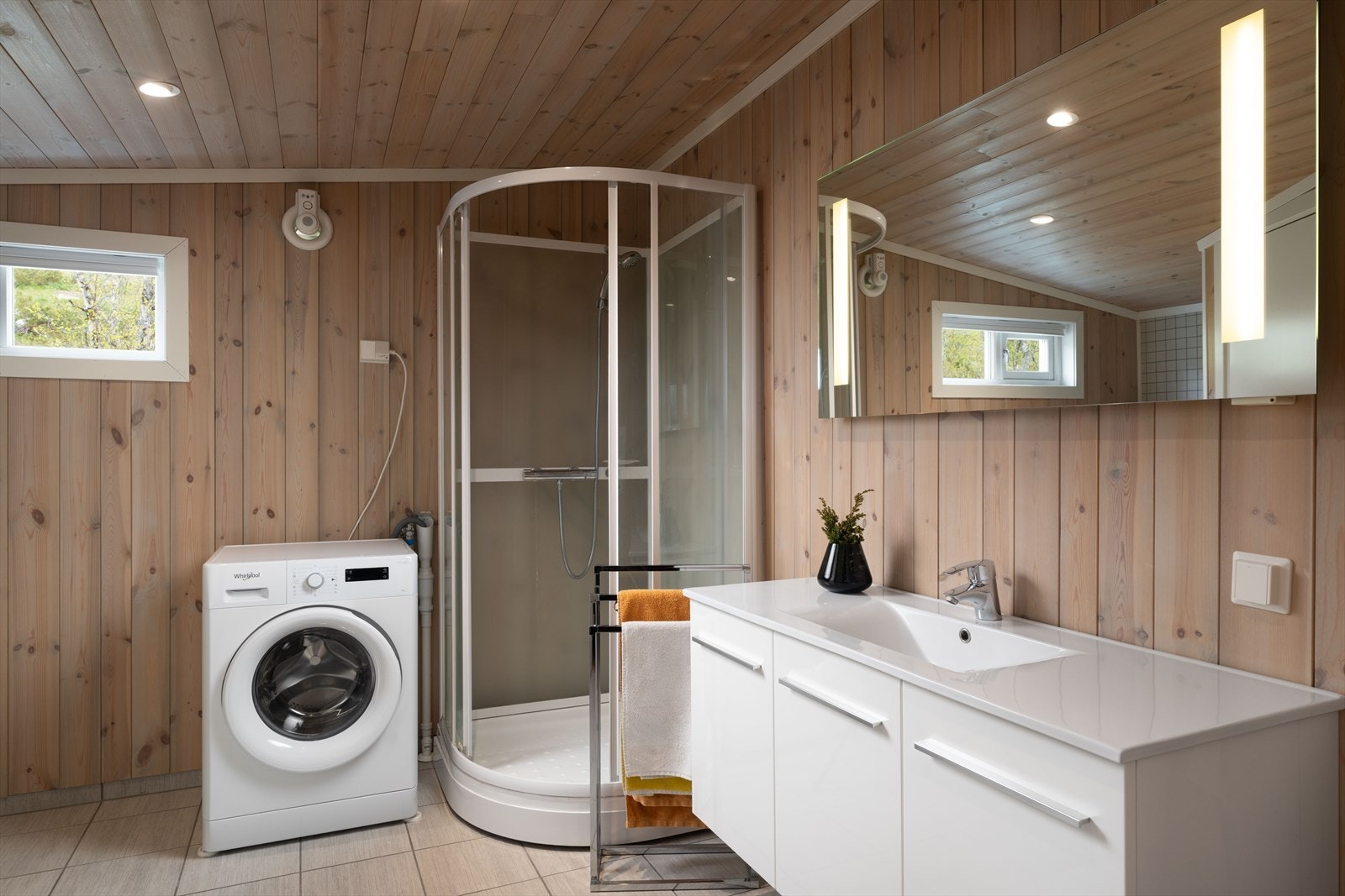 Badet har panel på vegger og i himling. Flislagt gulv med varmekabel. Rommet er innredet med baderomsinnredning med servant,
vegghengt toalett, dusjkabinett og opplegg for vaskemaskin. Galleribilde