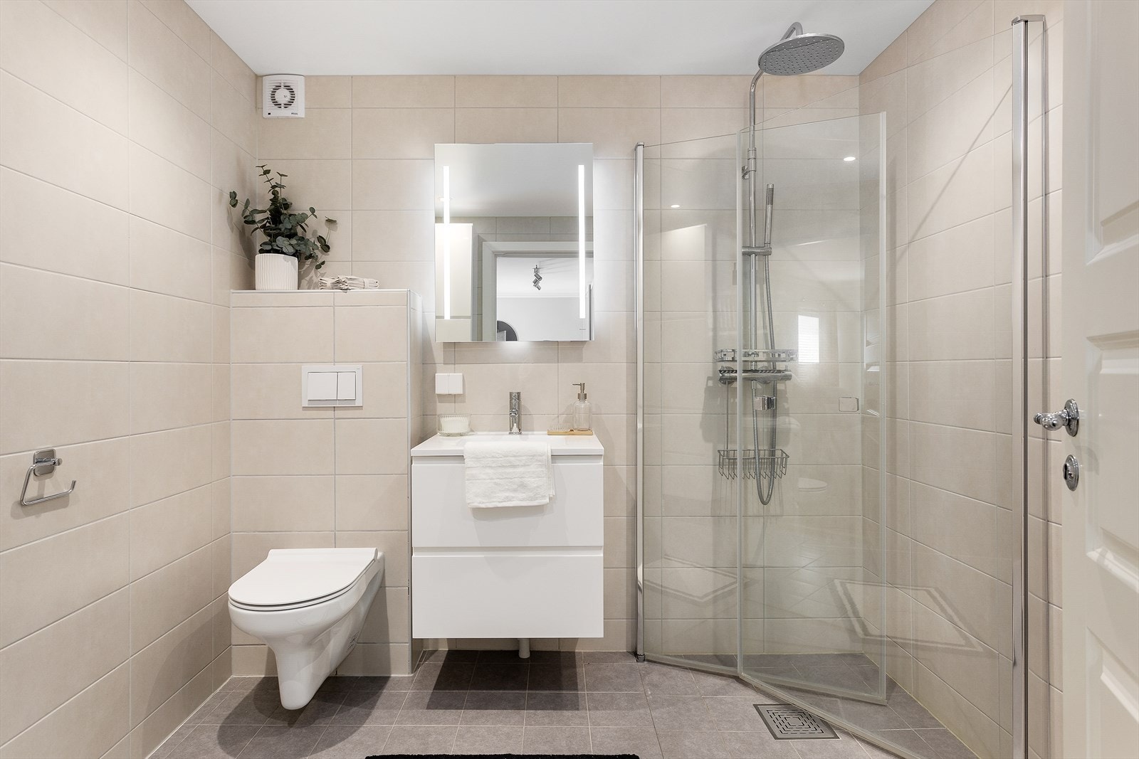 Badet ble oppgradert i 2023 og er lekkert innredet med to 60 cm høyskap og servantskap i hvite, glatte fronter. Galleribilde