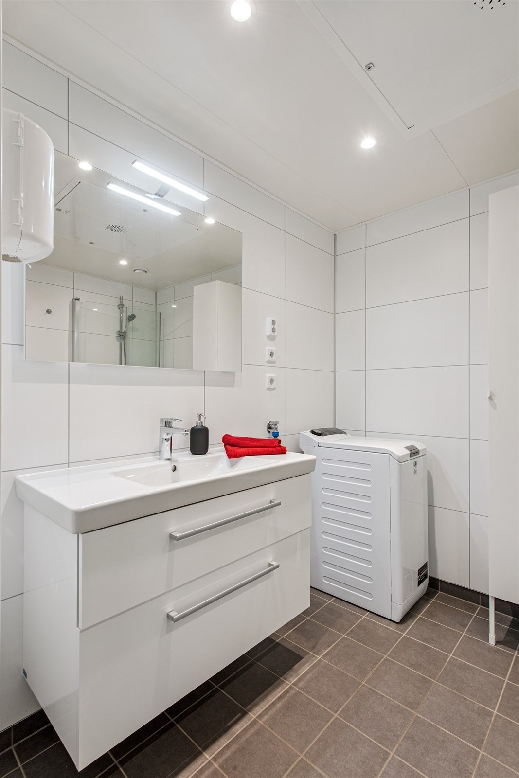 Badet har servantinnredning med skuffer, speil med belysning og opplegg for vaskemaskin. Galleribilde