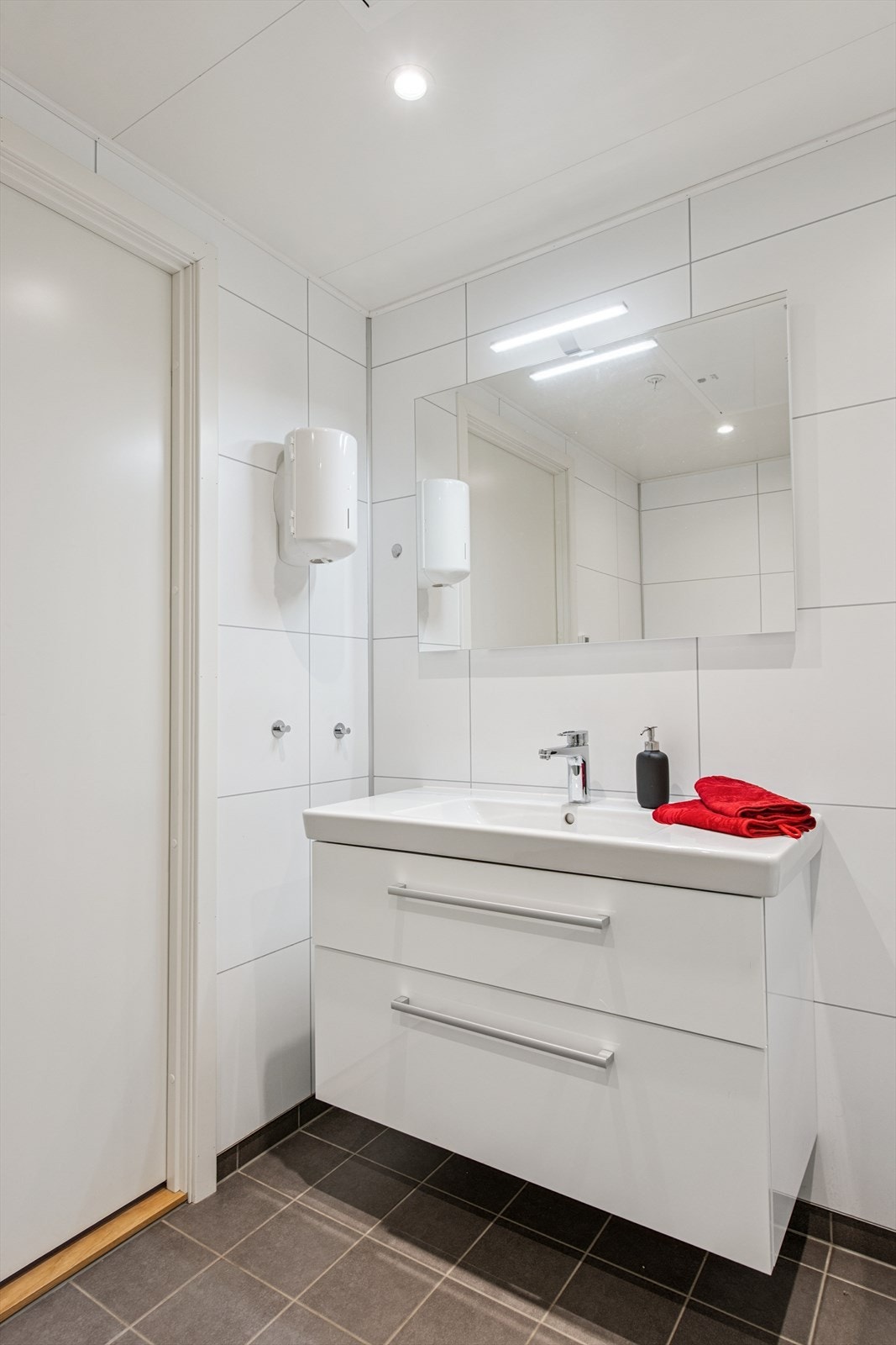 Heldekkende plate med servant i en praktisk baderomsinnredning med gode oppbevaringsmuligheter. Galleribilde