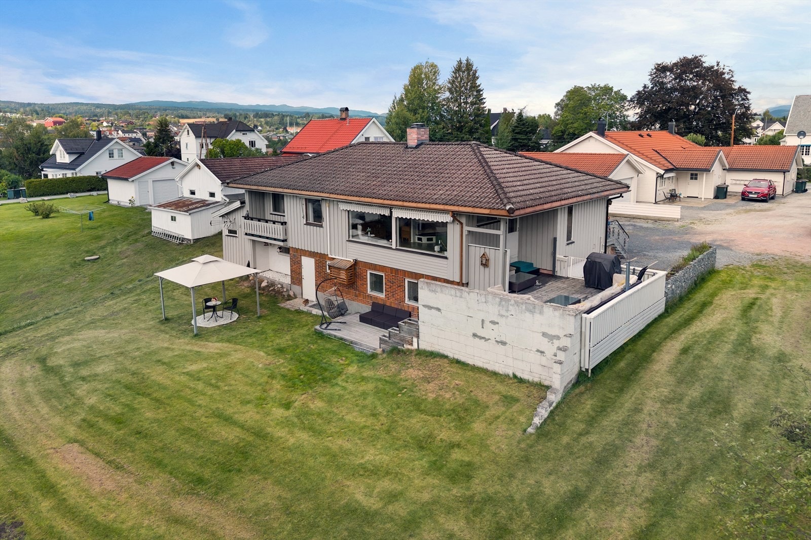 Tomten er opparbeidet med gressplen og blomsterbed av dekorstein og treverk Galleribilde