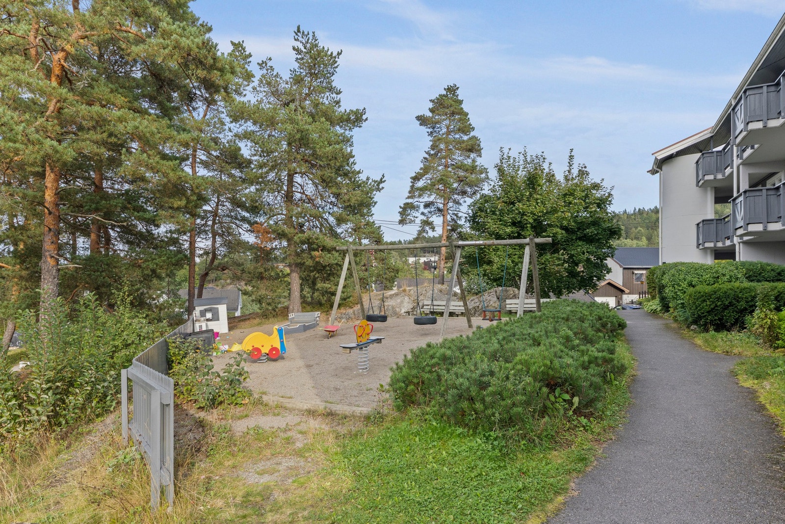 Felleseiendommen har asfalterte internveier, lekeplass, plenareal, trær og diverse beplantning Galleribilde