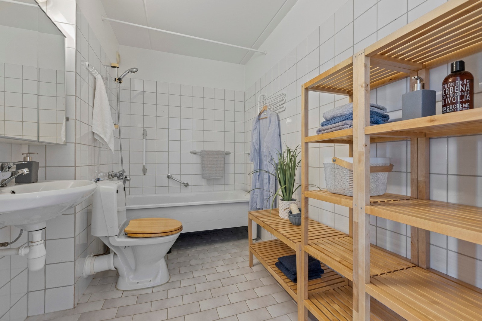 Badet har varmekabler, en enkel servant, speilskap, gulvstående toalett og badekar Galleribilde