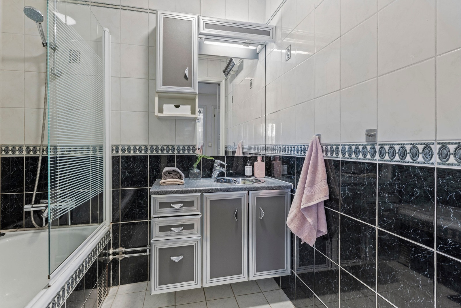 Badet er utstyrt med en nedfelt servant med oppbevaringsmuligheter og badekar Galleribilde