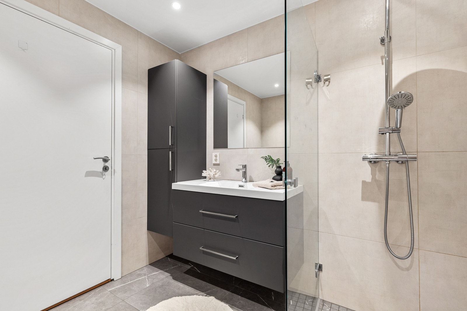 Rommet har innredning med nedfelt servant, vegghengt toalett og dusjhjørne med regndusj og glassvegg Galleribilde