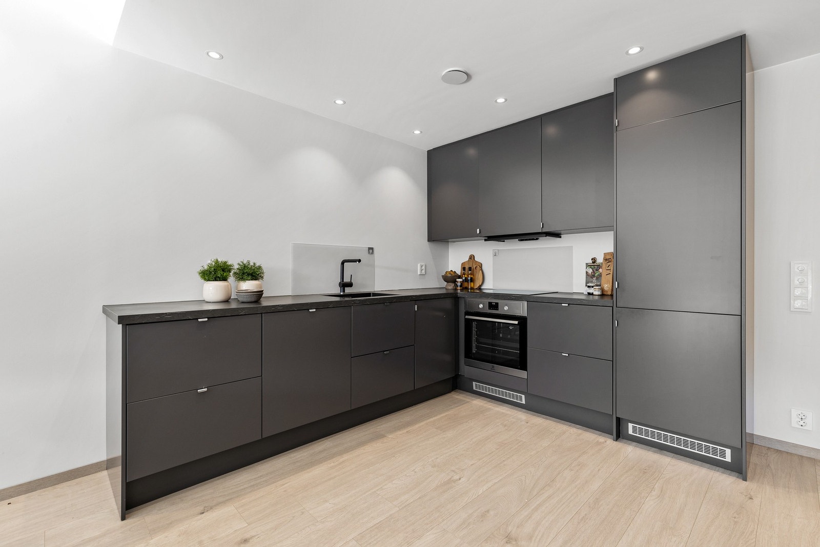 Innredningen har integrerte hvitevarer, herunder kjøl/fryseskap, oppvaskmaskin, platetopp og stekeovn Galleribilde