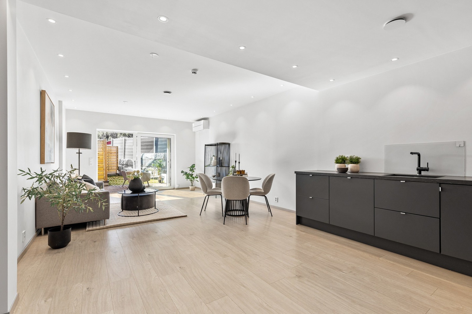 Lys og tiltalende stue med 1-stavs laminat på gulv, slette flater på vegger og downlights i himling. Galleribilde