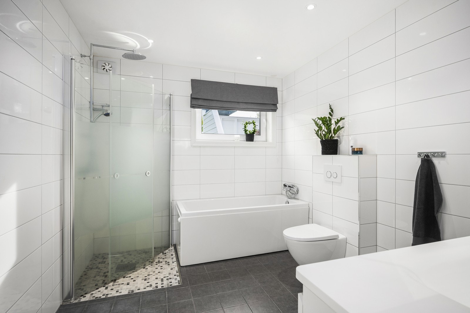 Lekkert bad fra 2014 med stor dusjnisje, badekar, vegghengt wc og servant innredning. Downligts og varmekabler. Galleribilde