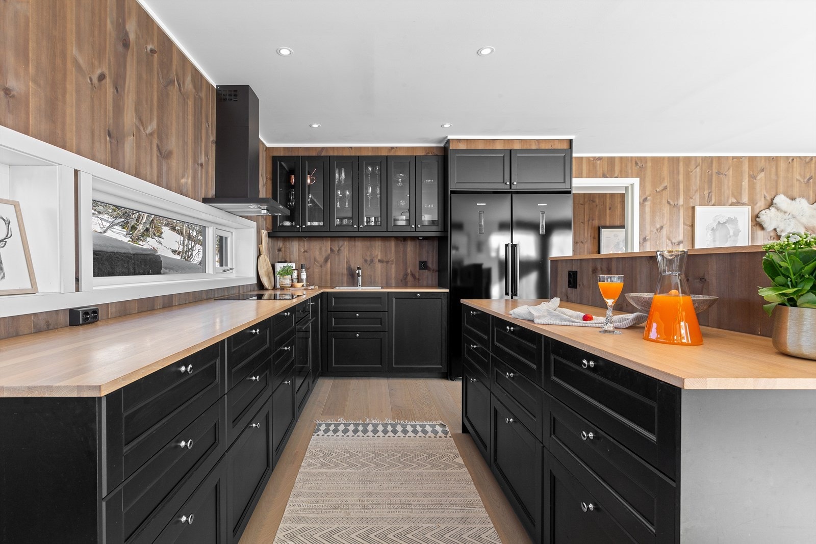 Stilig sort kjøkken med kontrasterende detaljer og vinduer som gir mye lysinnslipp Galleribilde